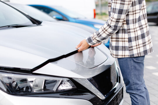 Young man checking under the hood of his car to figure out what the problem is.