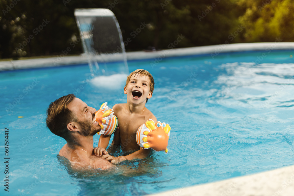 Wall mural playful father having fun with his little boy while being in swimming pool