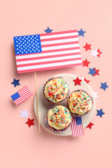 Plate with tasty patriotic cupcakes and flags of USA on pink background. American Independence Day