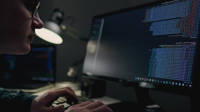 IT specialist works at a laptop computer writes code for a company. The job of a programmer is typing test code for writing web design. Young professional working at home, remote work
