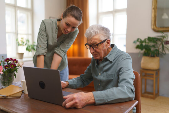 Granddaughter teaching grandfather how to use notebook. - Powered by Adobe
