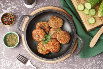 Frying pan with cutlets, dill and wooden board on grey grunge table in kitchen