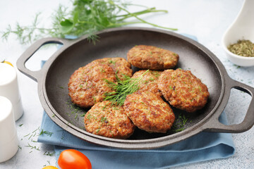 Frying pan with cutlets, dill and tomatoes on blue grunge table in kitchen