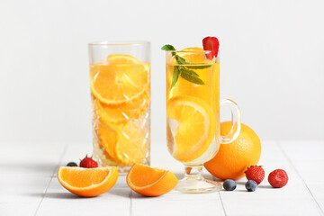 Glasses of infused water with orange slices on white tile background
