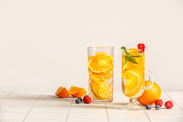 Fototapeta Glasses of infused water with orange slices on white tile background obraz