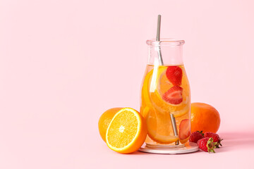 Bottle of infused water with orange slices on pink background