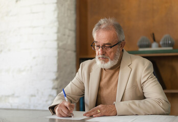 Serious eldery businessman signing document at office table.