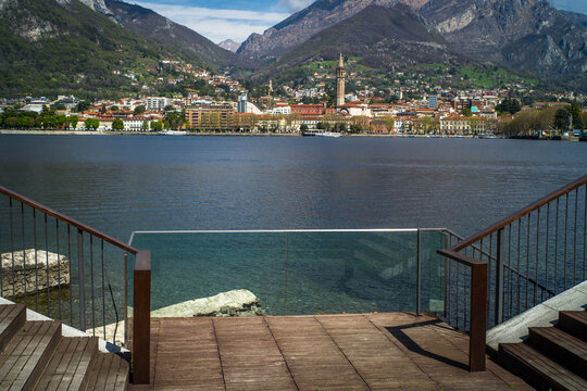 Buildings of the city of Lecco on the shores of Lake Como surrounded by mountains in the background. View from the promenade in Malgrate