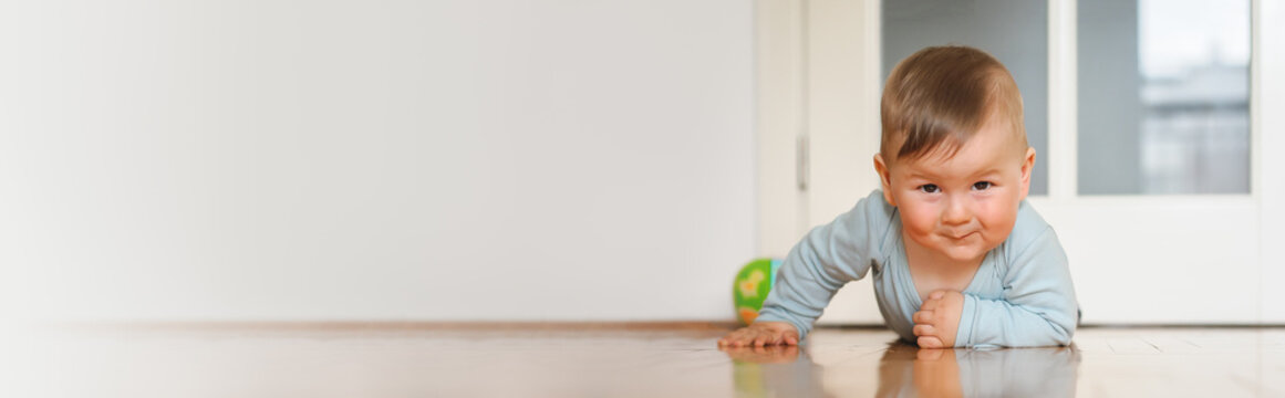 Cute baby boy crawls on the home floor, explore the world and learn to move. Banner. Place for text