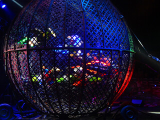 Group of five bikers performing maneuvers inside a spherical cage, known as the globe of death, at...