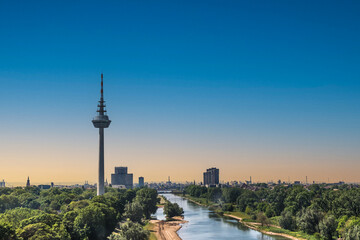 Obraz premium View to the Fernmeldeturm and river Neckar in Mannheim, Germany. Television TV telecommunications tower. Beautiful evening light. Copy space.