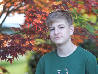 Outdoor portrait of a friendly caucasian blue-eyed teenager in a green t-shirt - 607534808