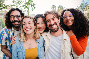 Portrait of a group of friends laughing together and looking at camera. Five young multiracial cherful people smiling and having fun. Joyful startup team coworkers celebrating and bonding together
