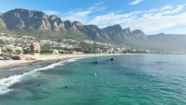 Aerial view of surfers in clear blue sea at Camps Bay, Cape Town, South Africa.
