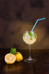 Lemon mint drink. A goblet with a straw. Ice cubes and mint in a glass. Soda with lemon and mint....