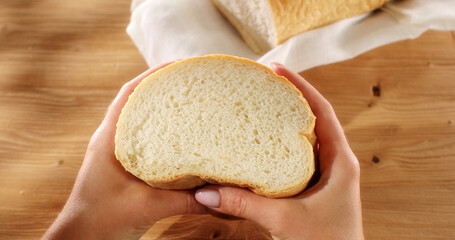 Female hands squeeze fresh bread. Check bread freshness. Wooden background. Slow mation. Sunny day....