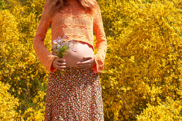 Close-up of young pregnant woman touching her belly and caring about her health.Pregnancy, maternity, preparation and expectation concept.Beautiful tender mood photo of pregnant woman. Young mom.