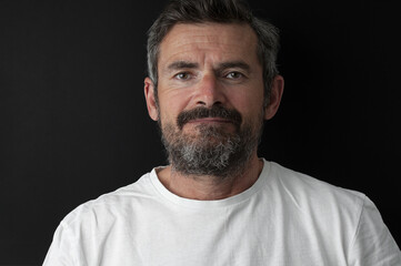 Fototapeta premium Portrait of aged beard man in white t-shirt close up on black background