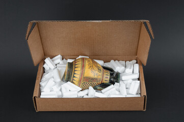 Antique vessel packed in cardboard box on black background