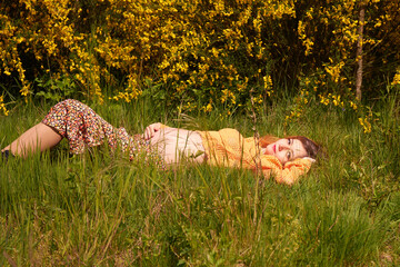 Beautiful pregnant woman lying on the grass in sunny day. Happy parenthood, healthy pregnancy,maternity, preparation and expectation concept.Beautiful pregnant woman relaxing in the park.Beautiful ten