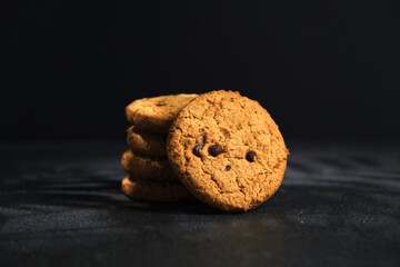 Oatmeal chocolate chip cookies. Cookies crumbs. Oatmeal cookies with chocolate on a black background with sunlight.