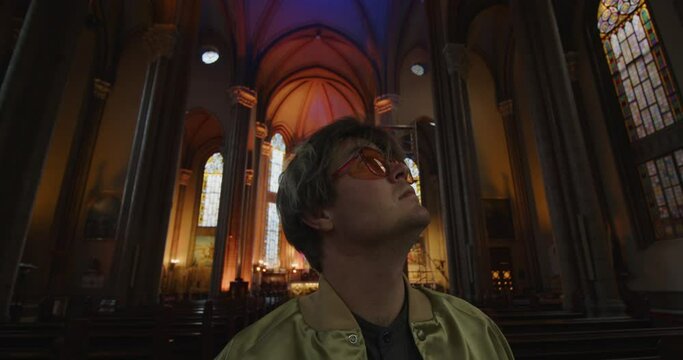 Stylish young attractive man in church rolls up his sleeves. An old Catholic church. The pastor is preparing to give a sermon. High quality 4k footage