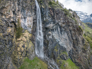 Sommer in den Alpen mit grünen Wiesen, Wasserfällen und Gletschern