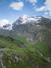Sommer in den Alpen mit gr&uuml;nen Wiesen, Wasserf&auml;llen und Gletschern