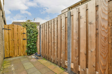 a backyard area with wooden fences and green plants growing on the side of the fenced off yard, - Powered by Adobe