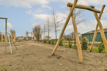 Fototapeta premium an outdoor play area with swings and wooden poles in the fore - image is taken from below, it's blue sky