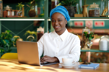 Fototapeta premium Happy african woman independent contractor working from cafe, copy space