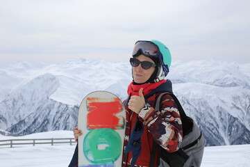 Woman snowboarder standing in the snowy mountains.