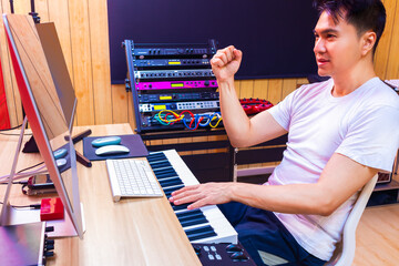 friendly asian male music producer enjoy arranging music on computer in home studio. music...