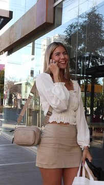 Joven Latina de compras habla con su telefono de forma sonriente 
