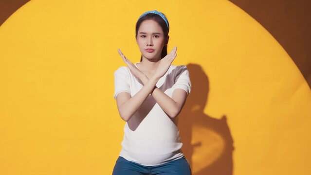 confused and say no hand gesture sign asian female pregnant woman listen look at camera while hand rising up make x cross symbol for refuse or say no to camera studio shot,pregnant woman hand defense