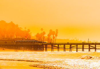 Surfers at San Clemente pier in the golden light of a summer sunset in Southern California - 607561633