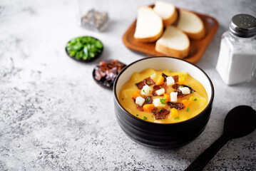 Potato carrot soup with fried bacon slices in a bowl