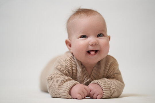 A newborn baby sticking out his tongue and smiling. Baby studio photography