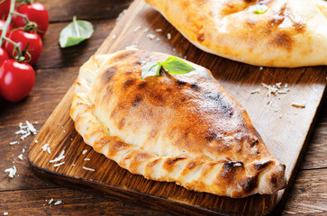 Delicious Pizza Calzone, Traditional Italian Pizza with Tomatoes and Fresh Basil on Wooden Background
