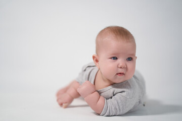 Portrait of a Baby in a gray jumpsuit, the photo was taken in a bright studio