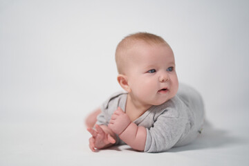 Portrait of a Baby in a gray jumpsuit, the photo was taken in a bright studio