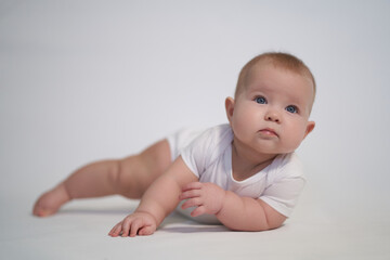 A newborn baby is trying to roll over on his stomach. photography on a light background