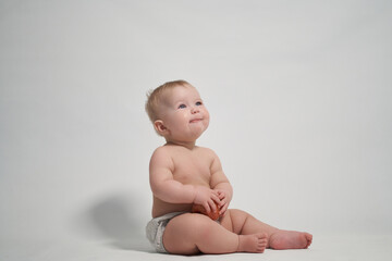 a child of 7 months sitting on the pope smiles holding a red apple in his hands.