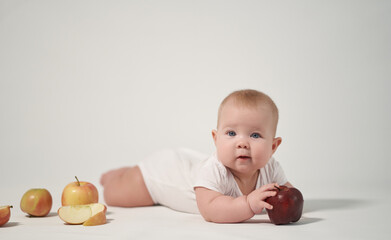 newborn baby among apples, photography on a light background