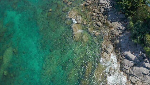 Top down seashore. Waves crashing on rock cliff. Beautiful sea surface in sunny day summer background Amazing seascap on Kata beach, Phuket.