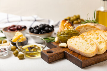 Ciabattas, olive oil in a bowl with olives, herbs, spices, garlic, pesto, parmesan and ciabatta bread on a texture background.Banner. Healthy food concept.Delicacy. Mediterranean Kitchen. Copy space.