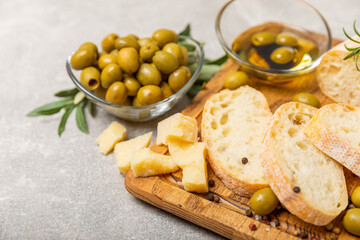 Ciabattas, olive oil in a bowl with olives, herbs, spices, garlic, pesto, parmesan and ciabatta bread on a texture background.Banner. Healthy food concept.Delicacy. Mediterranean Kitchen. Copy space.