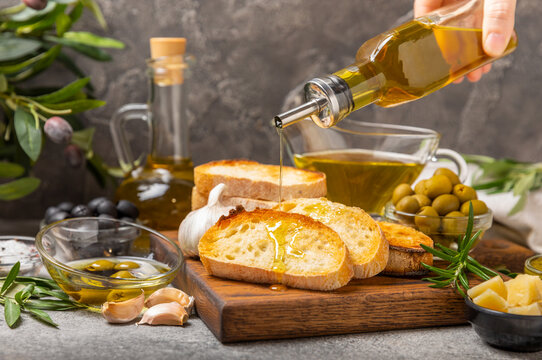 Ciabattas, olive oil in a bowl with olives, herbs, spices, garlic, pesto, parmesan and ciabatta bread on a texture background.Banner. Healthy food concept.Delicacy. Mediterranean Kitchen. Copy space.