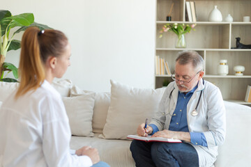 Senior man doctor examining yound woman in doctor office or at home. Girl patient and doctor have consultation in hospital room. Medicine healthcare medical checkup. Visit to doctor