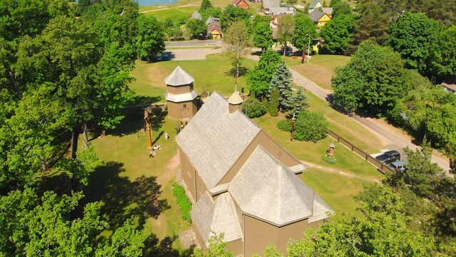 Young lithuanians relax by St. Joseph Church in Paluse, Lithuania. Stave Churches in Europe. Old heritage sites. Walls formed by vertical wooden boards.